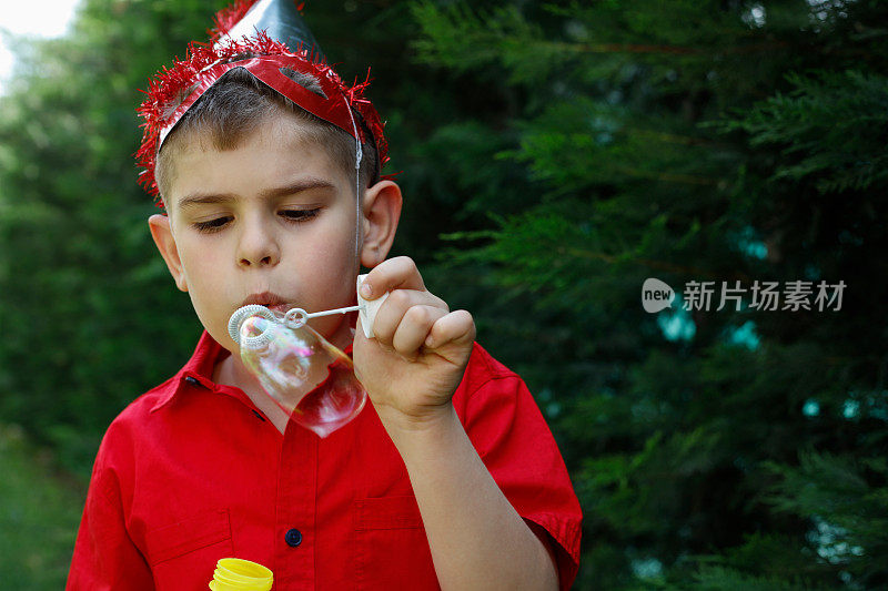 可爱的男孩在大自然中吹泡泡玩得很开心