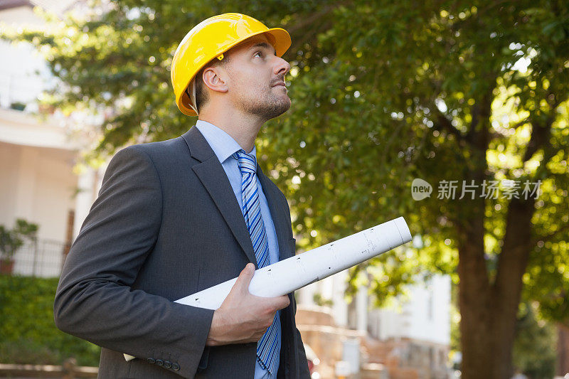 年轻的男建筑师带着蓝图在户外