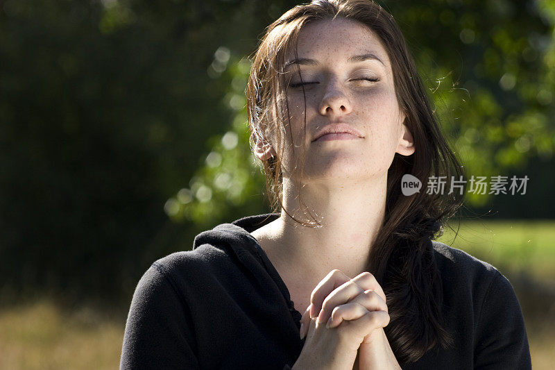 年轻女子在阳光下祈祷