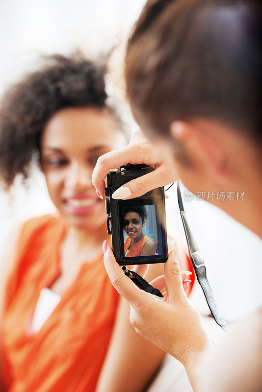 一个女人用数码相机给她的朋友拍照。