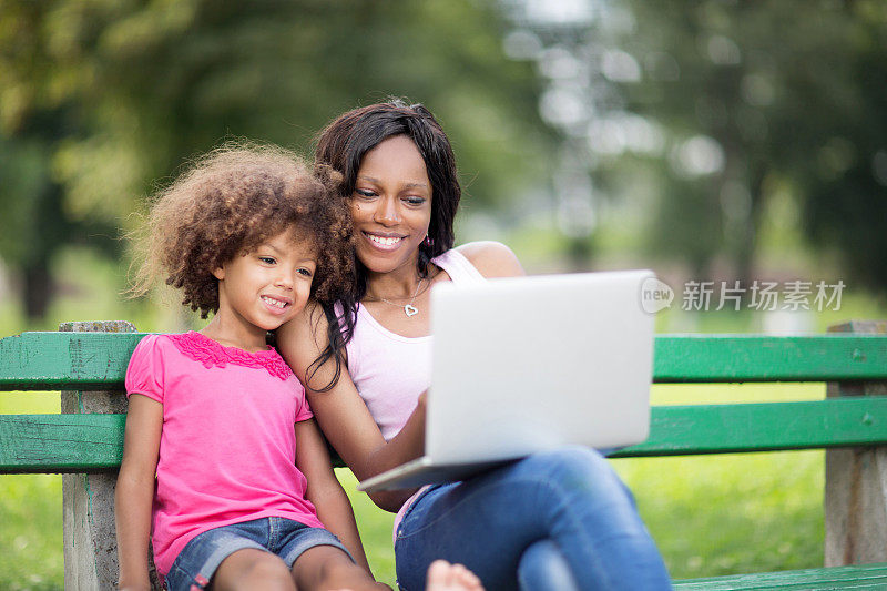 妈妈和女儿在公园里用电脑。