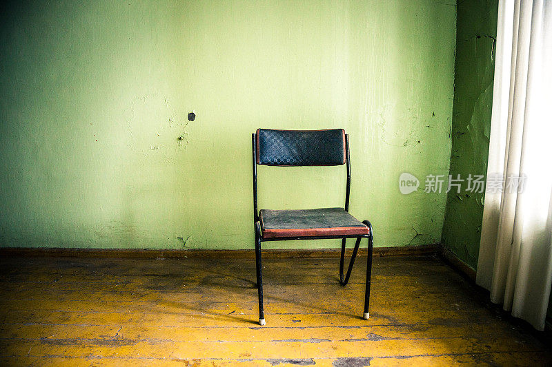 旧椅子靠着一堵绿墙在废弃的房子