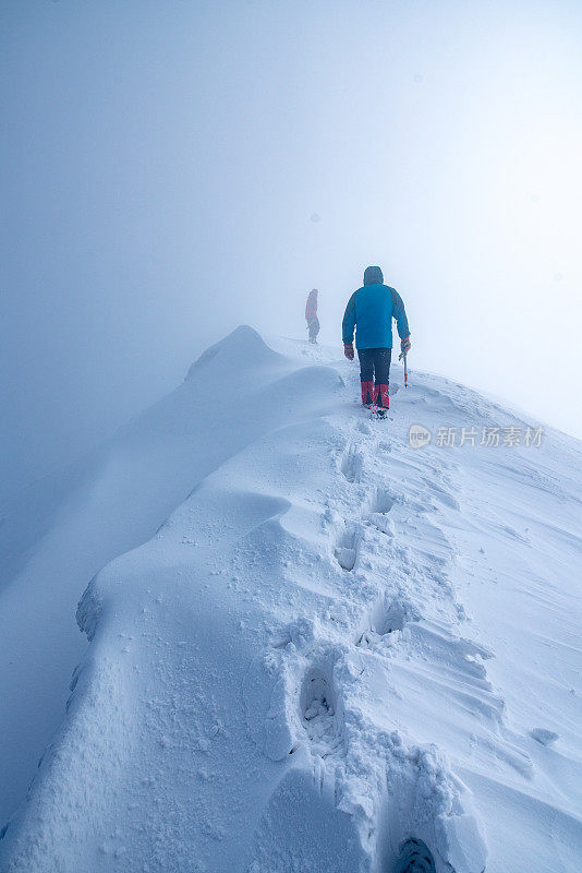 两个人走在雪山的山峰上进入云中