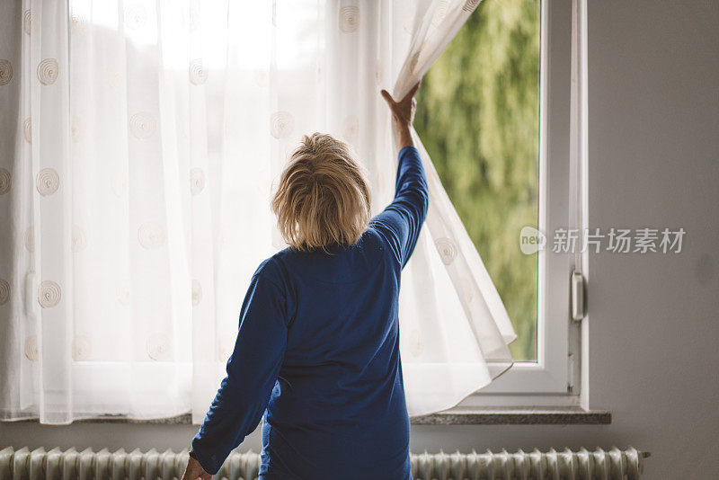 女人拉开窗帘向外看