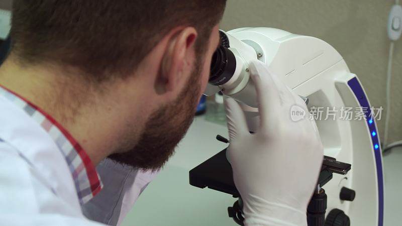 在实验室里，人转动显微镜上粗糙的调节旋钮