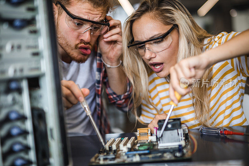 两个大学生试图在一个实验室修理主板。