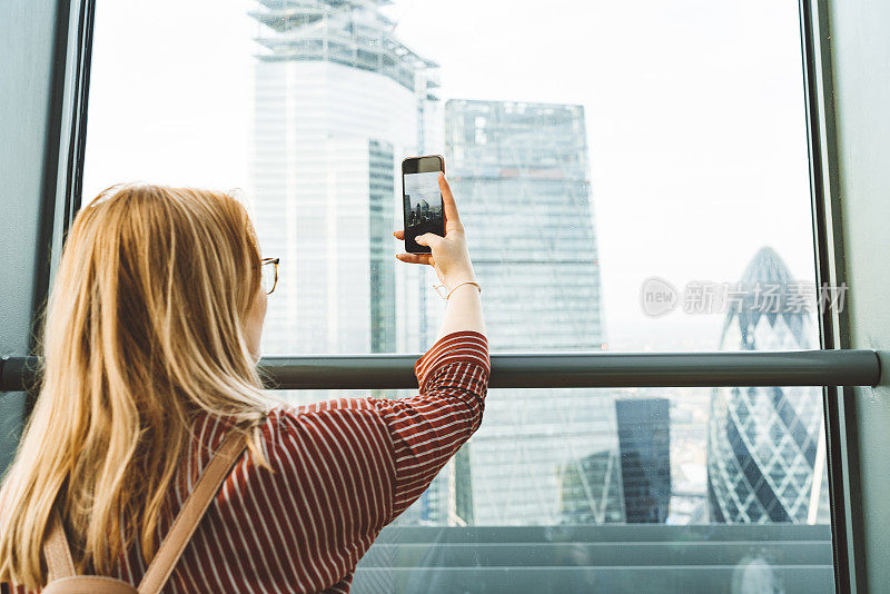 年轻女子在现代摩天大楼拍照