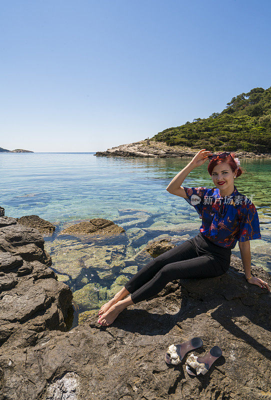 年轻漂亮的女人坐在克罗地亚Mljet岛海边的岩石上