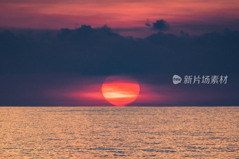 海上史诗般的日落。巨大的太阳掠过海洋。