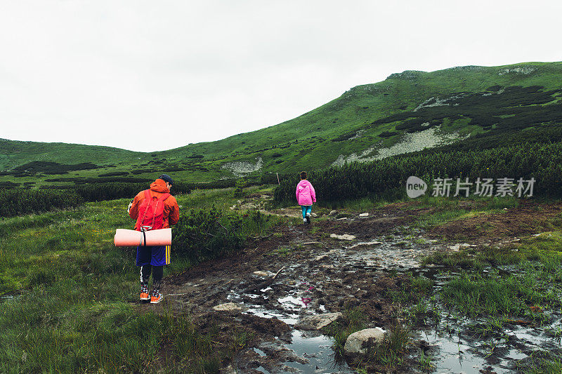 一名女子和一名男子背包客正在穿越山间的泥泞小路