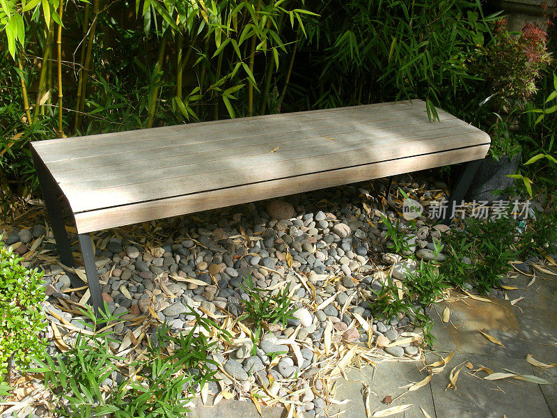 木凳的特写图像旁边的石板和卵石小径与竹篱的背景，观赏花园与日本特色