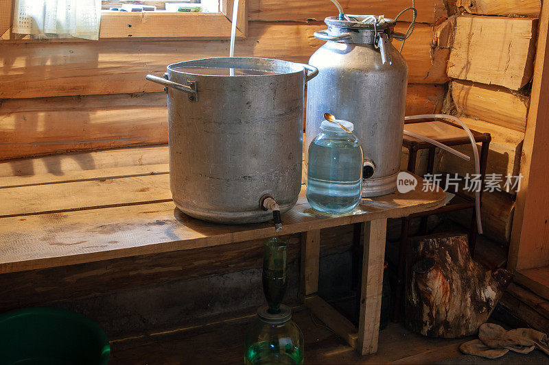 在一个村庄的浴室里用原始的私酿烈酒蒸馏器准备私酿烈酒的过程。月光。在俄罗斯制造私酿烈酒。