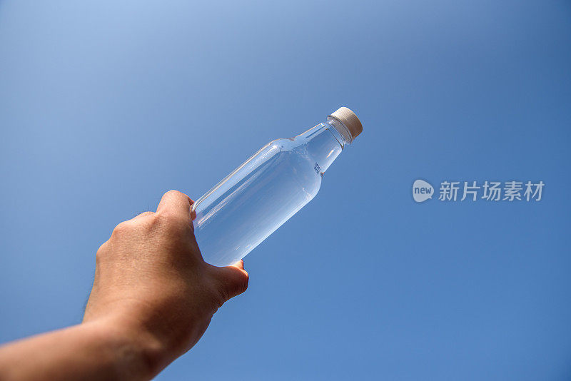 在蓝天里，男人手里拿着晶莹剔透的水瓶