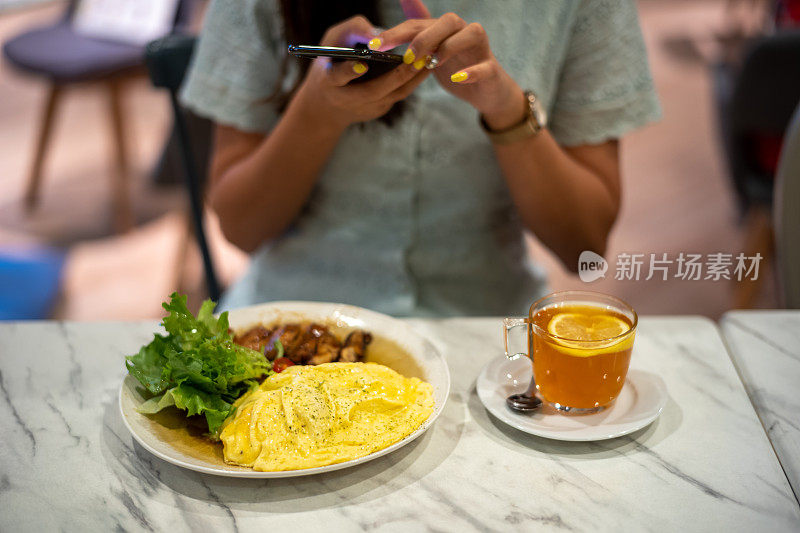 一名年轻的亚洲女子正在给桌上的鸡和蛋饭拍照