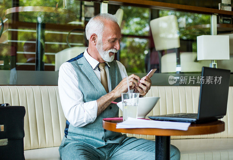 一位在咖啡馆里使用智能手机的老人