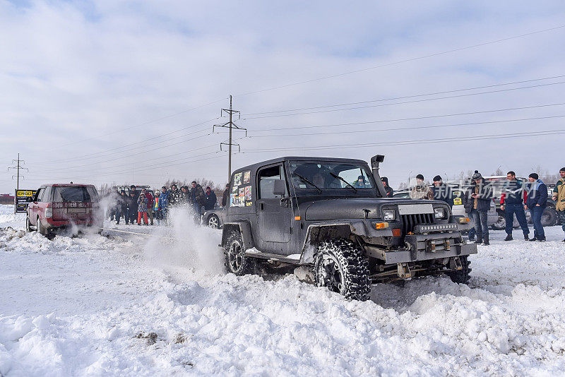 越野越野车“吉普牧马人”4x4越野训练在雪地里转动轮子拉着缆车“路虎”在人群中。