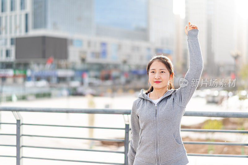 亚洲年轻女子站和伸展后，在城市跑步