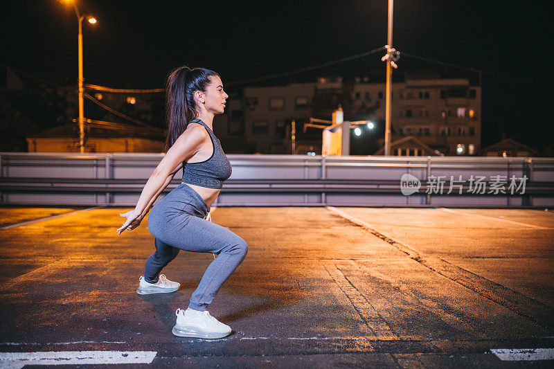 年轻女子在晚上跑步后做伸展运动