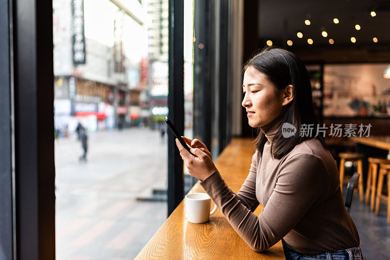 年轻的亚洲女性在咖啡店里使用智能手机