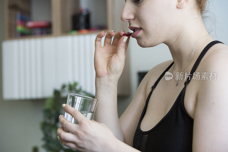 年轻女子拿着药和一杯水