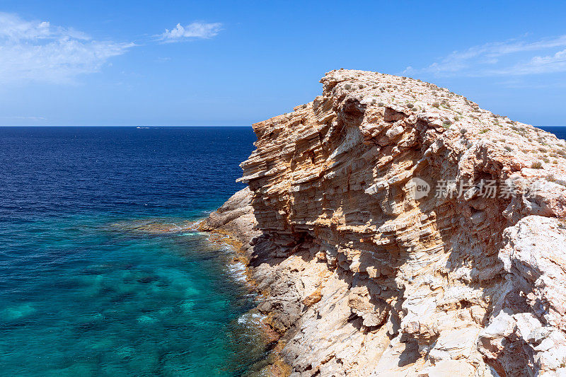 蓬Galera角。西班牙巴利阿里群岛的伊比沙岛。在碧绿的大海里，一个冻结在石头里的波浪。