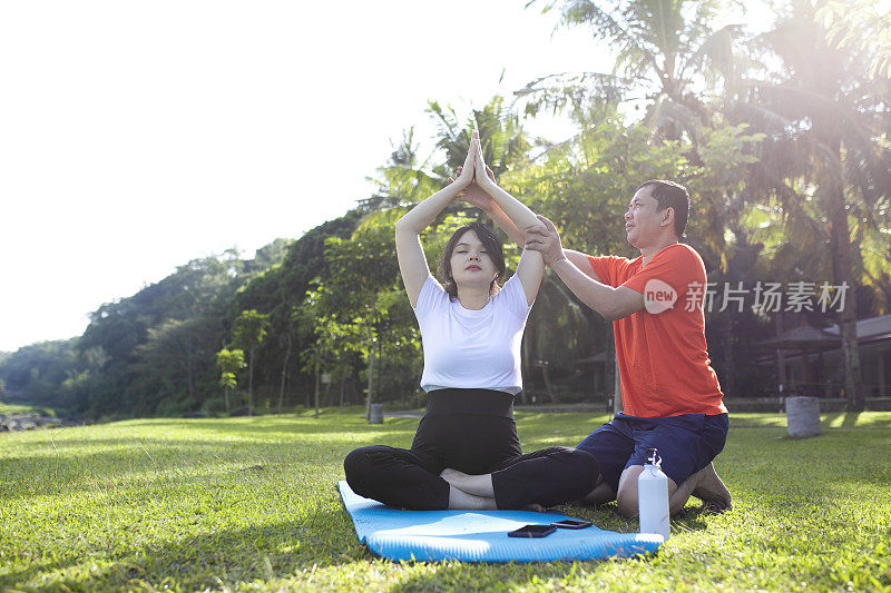 年轻的亚洲孕妇在她丈夫的帮助下做运动