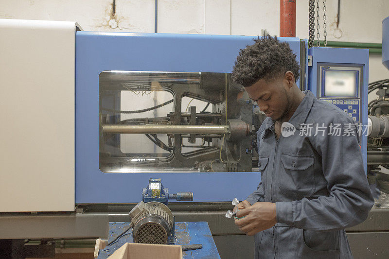 年轻的非裔美国工人在工厂里使用重型机械