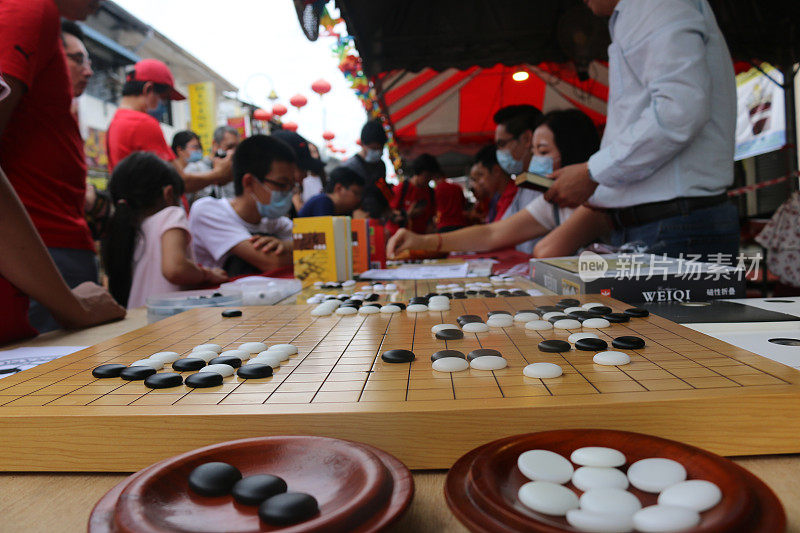 在乔治敦的一条街上，戴面具的人们在玩中国围棋和围棋
