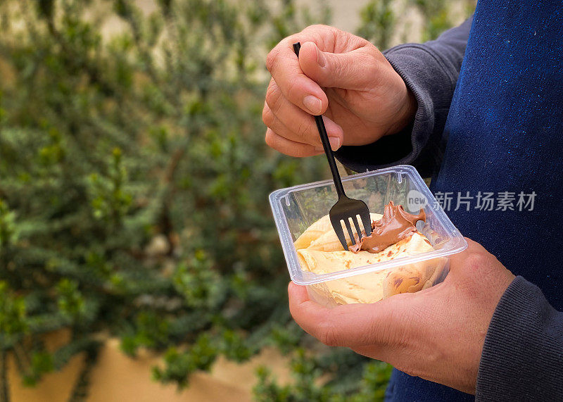 手拿着一个装着巧克力可丽饼的塑料容器在阳台上