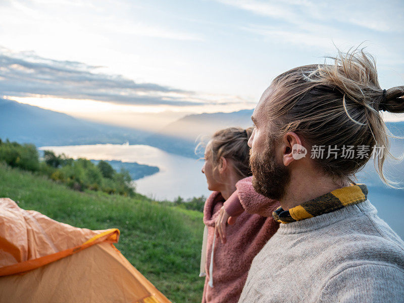 一对夫妇在山顶露营，日出