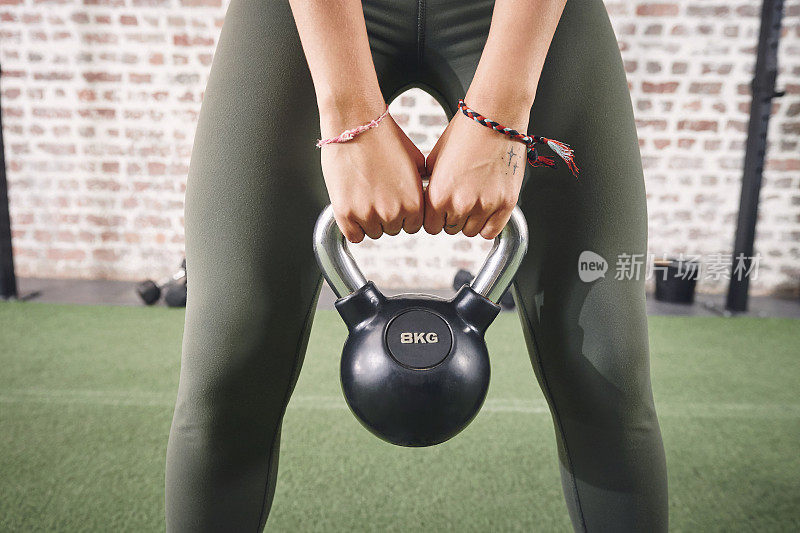 一个运动的年轻女子在健身房用壶铃锻炼的照片