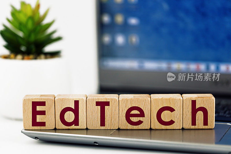 图片上的教育科技主题。笔记本电脑的背景上写着“EdTech”的木质立方体，多汁多汁