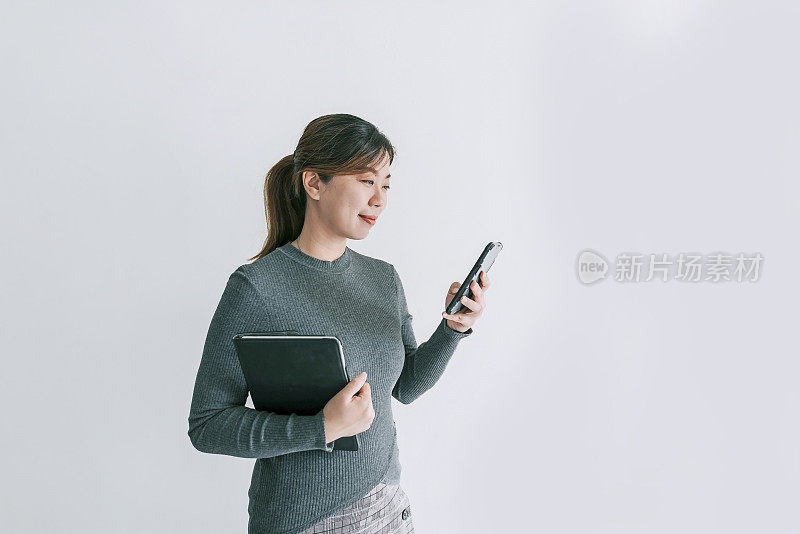 亚洲华人中年女性微笑着用白色背景的智能手机视频通话