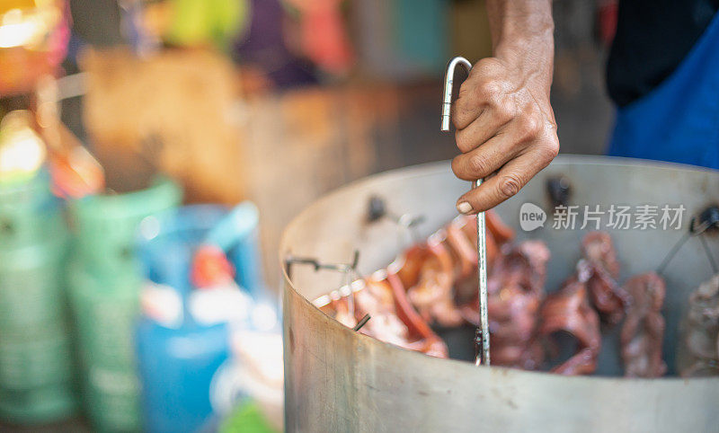 男手握钢肉和烧烤类腌制肉类在铝锅与木炭准备出售或服务给买家。