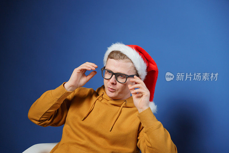 一名戴着圣诞老人圣诞帽的男子正要摘下他的眼镜。