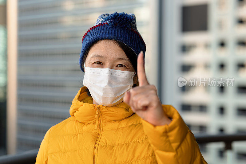 戴着口罩，手指向上的女人