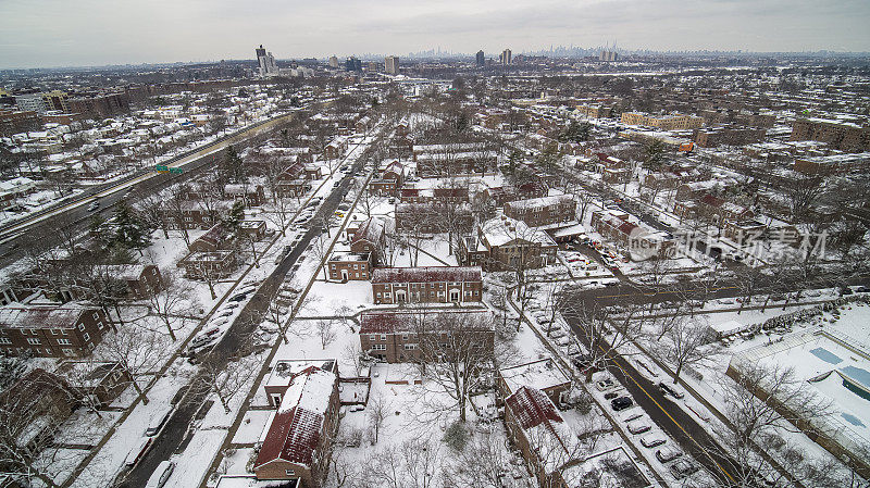 一场暴风雪过后的冬天，在皇后区牙买加的Parkway村社区鸟瞰图，遥望地平线上的曼哈顿天际线。