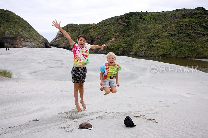 孩子们穿着扎染t恤在海滩上跳起来