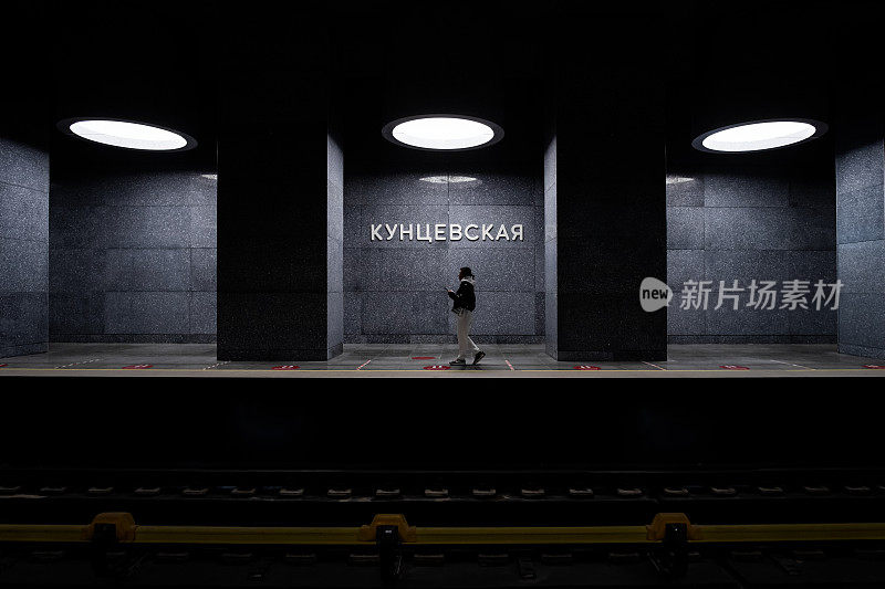 空无一人的地铁站里，一个女孩独自在天花板的灯光下