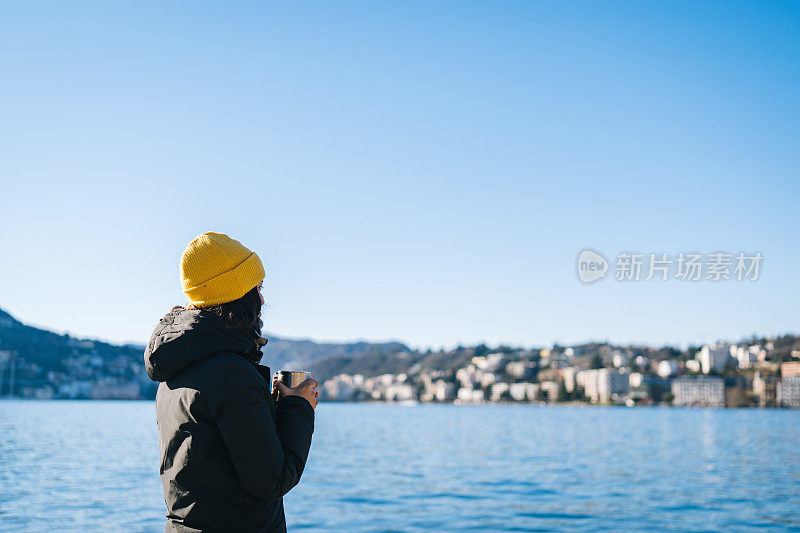 年轻女子在湖滨边喝着热饮