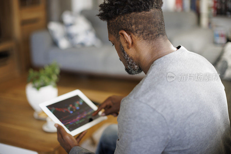 男人在家里用数码平板电脑查看股票和加密货币市场