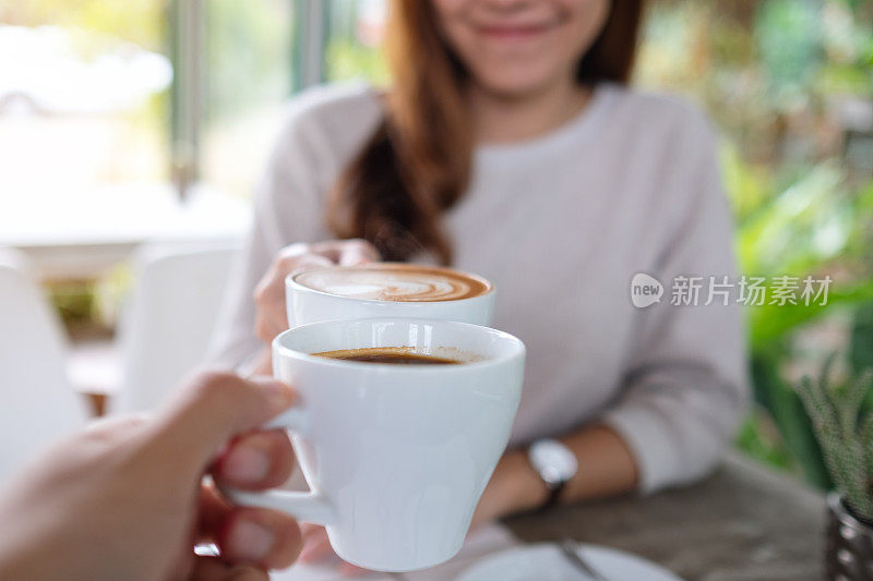 一对夫妇在咖啡馆里碰咖啡杯的特写照片