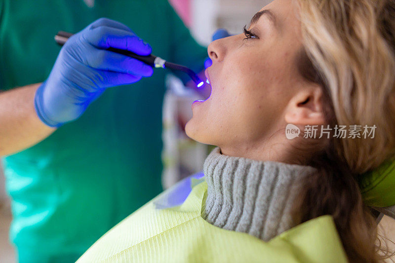 无法辨认的男性牙医使用紫外线灯硬化牙齿填充物