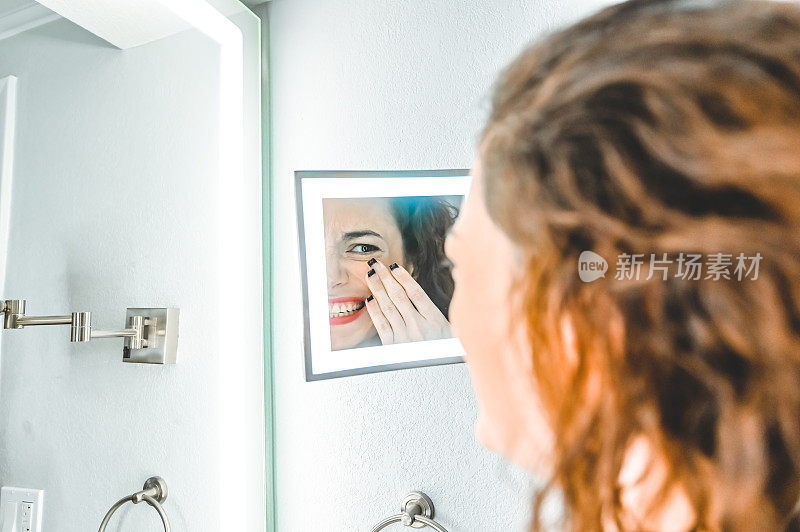 一个家庭浴室里的女人皱着眉头看着梳妆镜，也许是对自己的外表不满意
