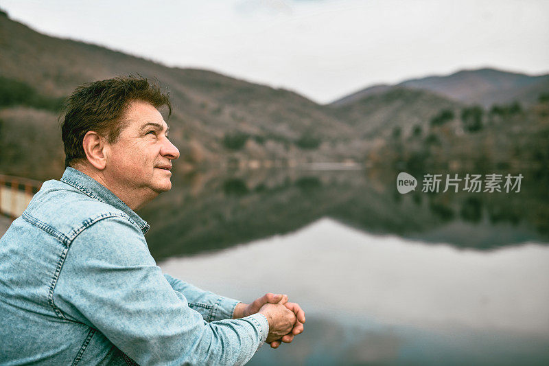 在湖泊日落时，老年男性探索未来的新鲜空气、享受和灵感