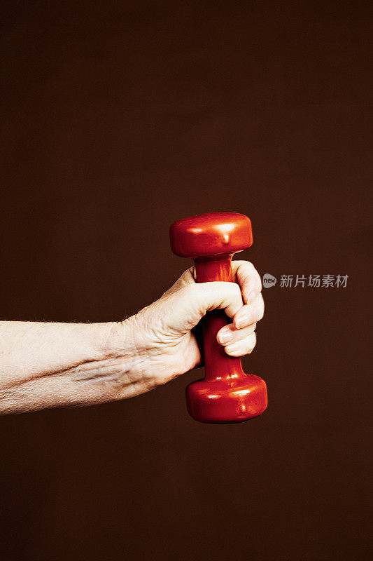 老年养生:老妇人手里拿着一个红色哑铃