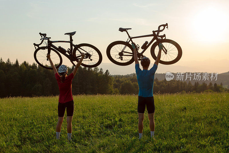 两个剪影把自行车举过头顶，摆出胜利者的姿势