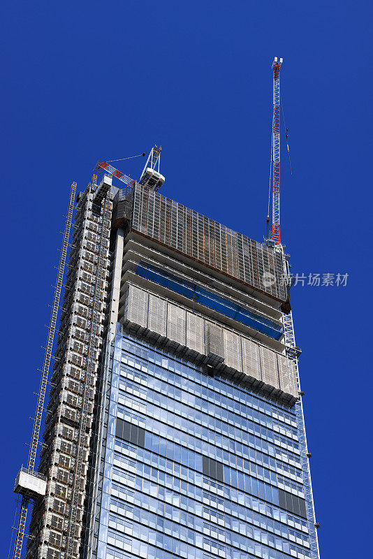 正在施工的城市建筑的一部分，上面有蓝天和起重机