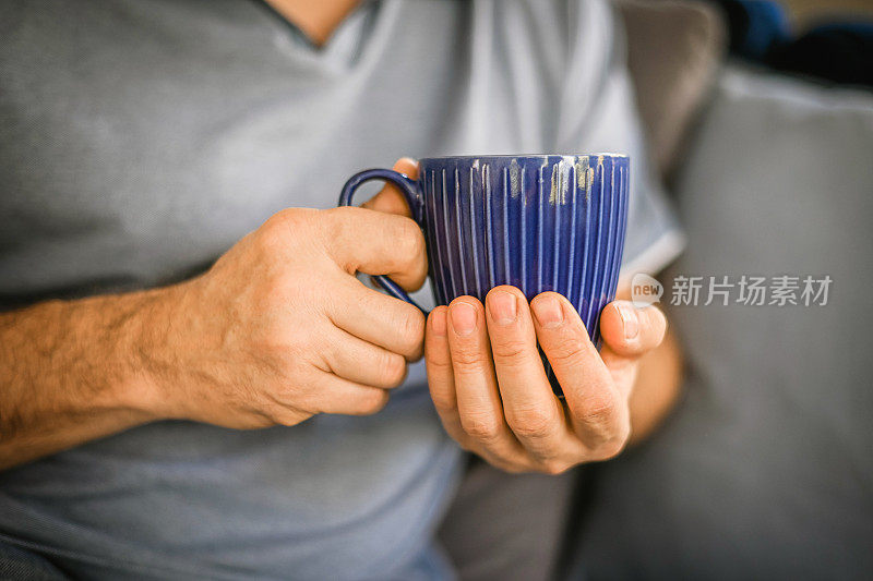 男人用蓝色杯子喝茶