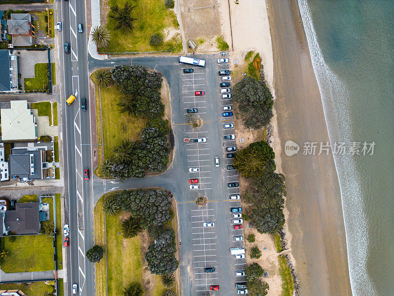 鸟瞰海边的城镇，有公路、房屋和停车场。